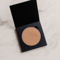 Candid Naturals Bronzer Pressed Powder compact open on a marble surface