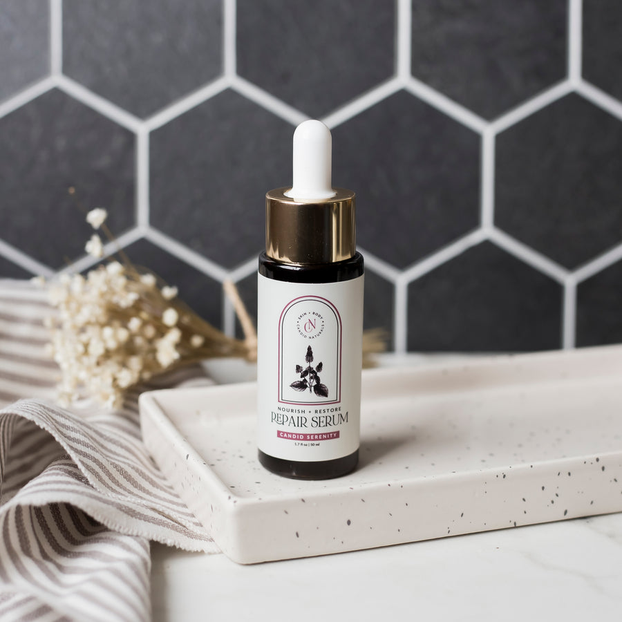 Candid Naturals Herbal-Infused Repair Serum bottle with dropper on a tiled background