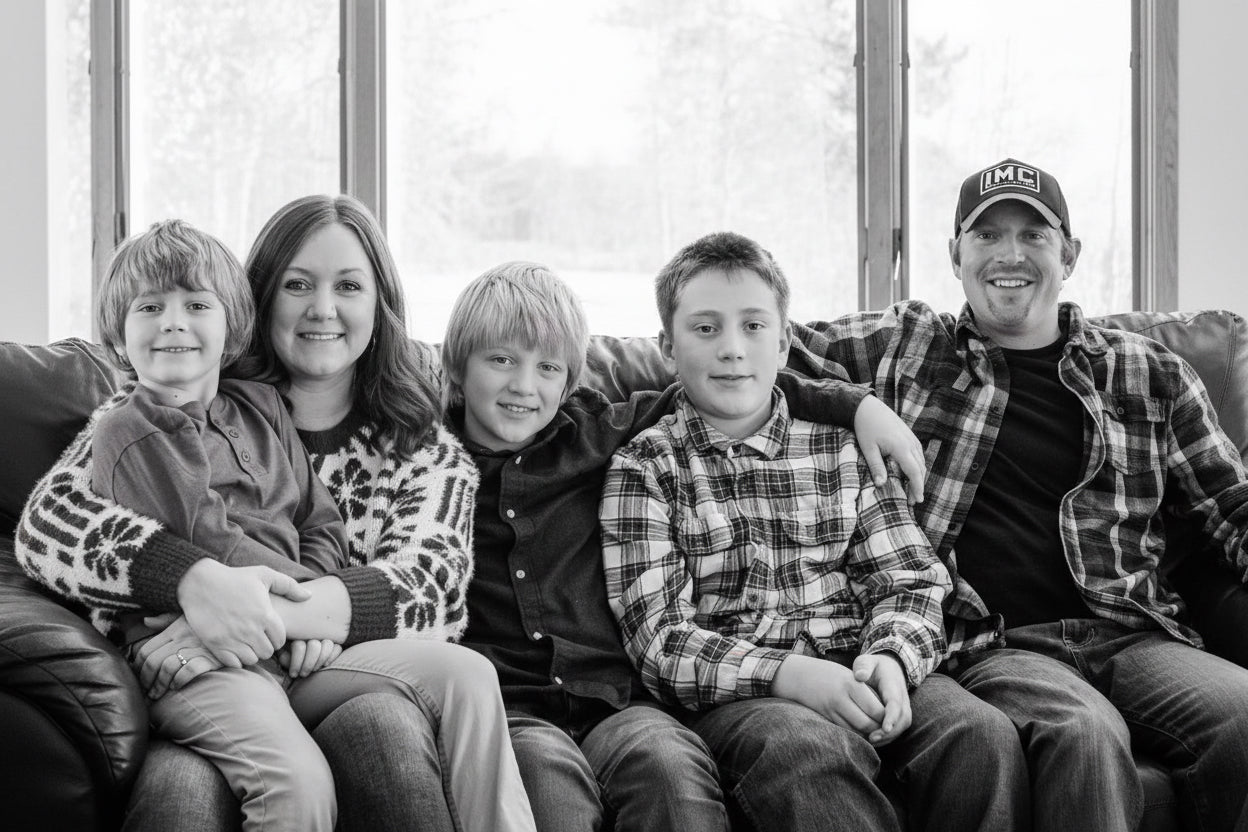 Family of five sitting together in front of a decorated Christmas tree.