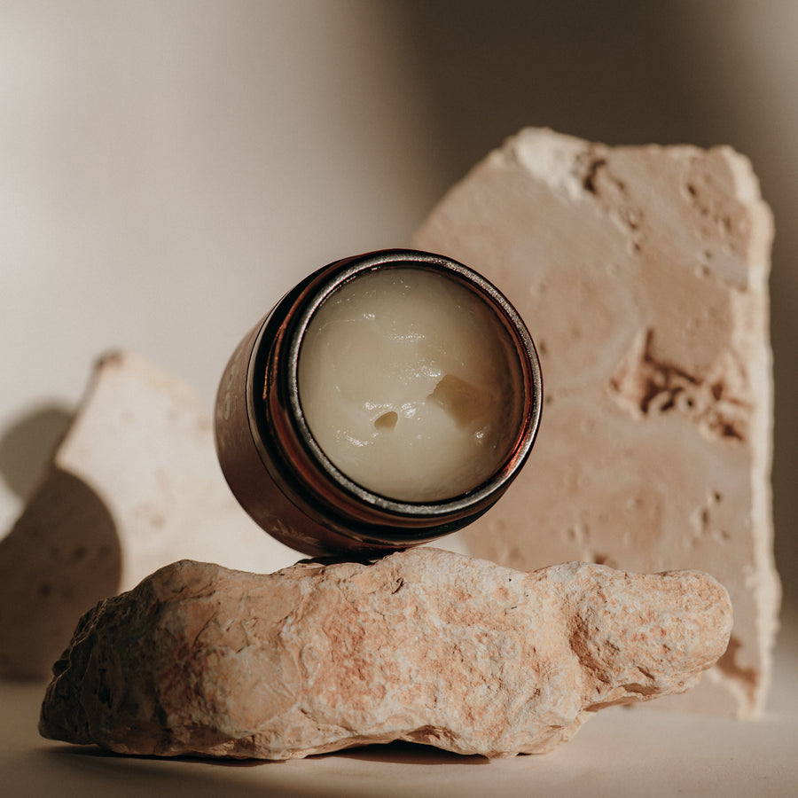 Candid Naturals Face Balm open jar on a pink stone with soft natural light
