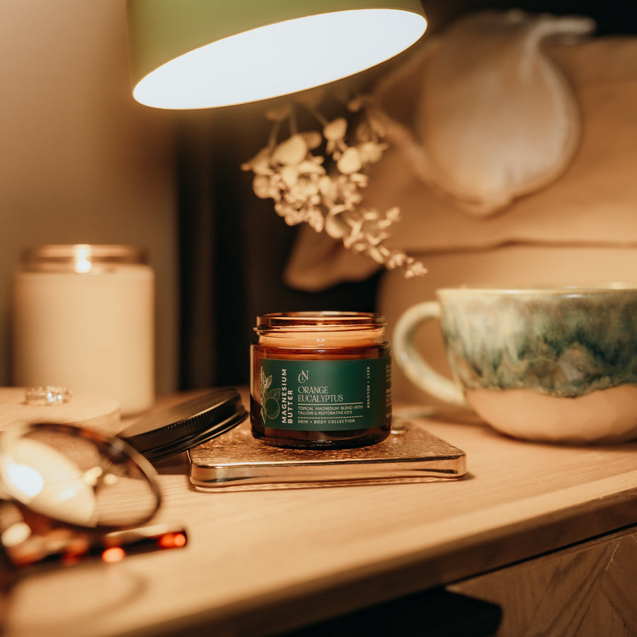 Candid Naturals Orange Eucalyptus Magnesium Butter jar displayed on a wood shelf